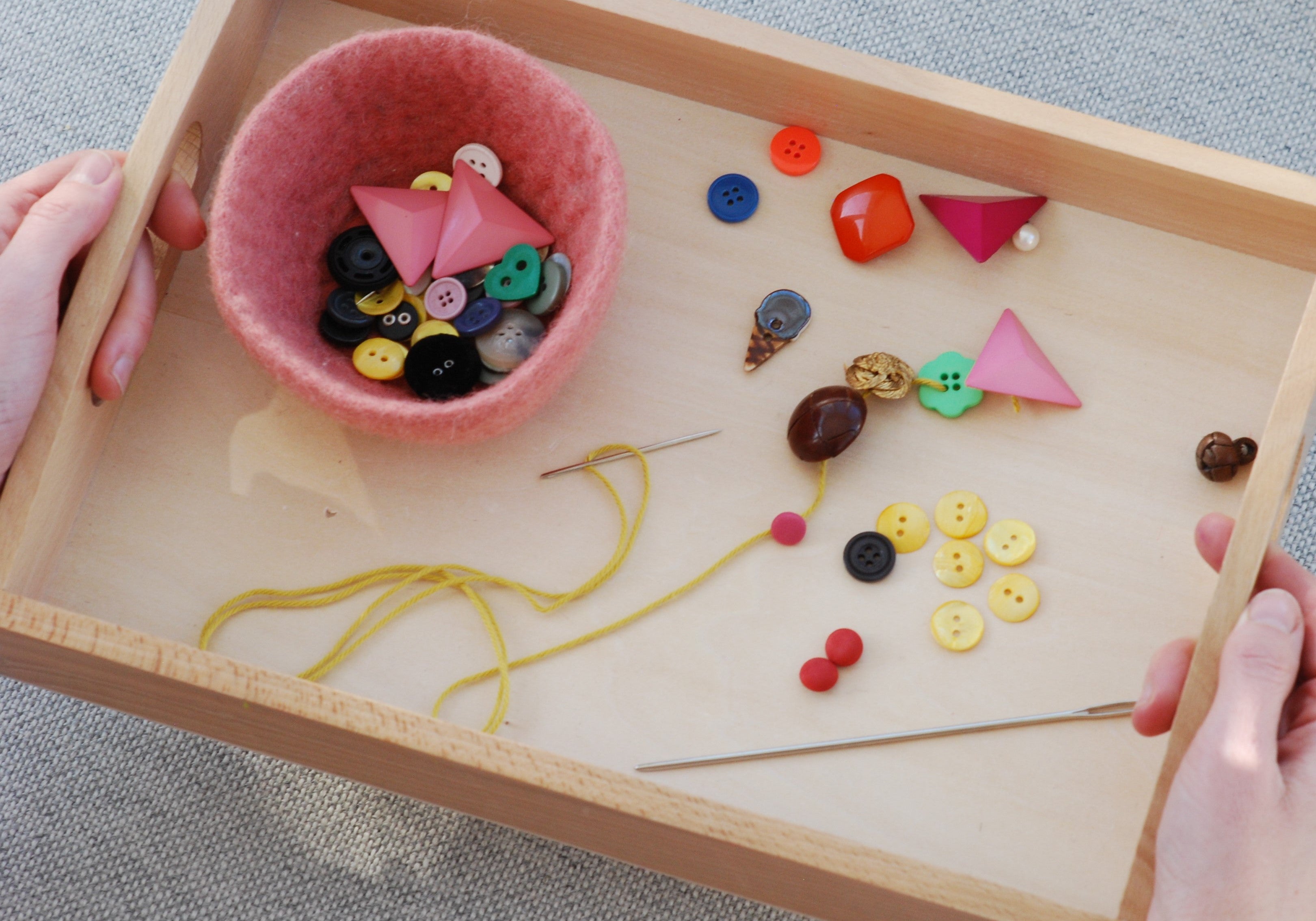 Et Montessori brett med perler som kan tres på en snor for å styrke finmotoriske ferdigheter hos barn