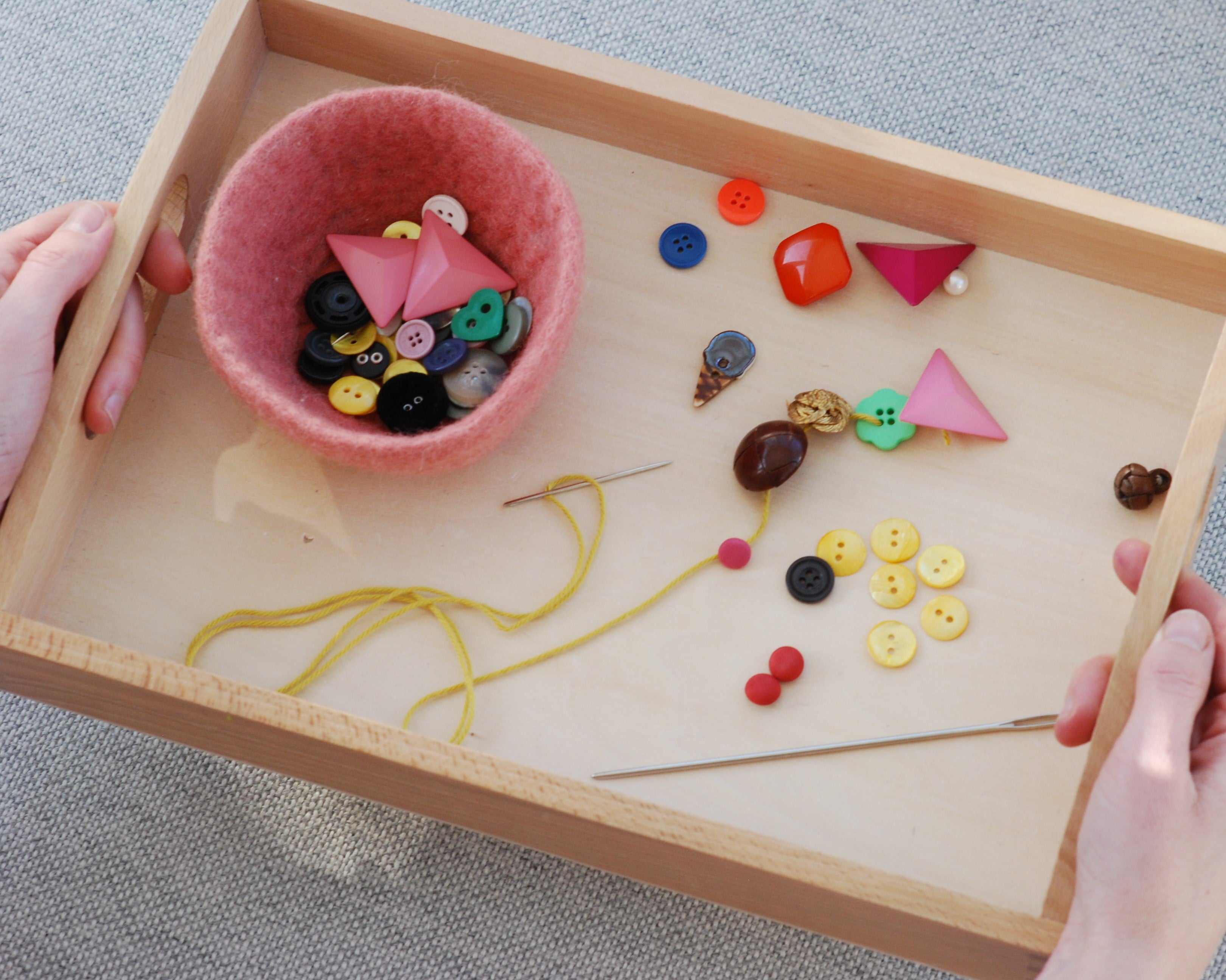 Et Montessori brett med perler som kan tres på en snor for å styrke finmotoriske ferdigheter hos barn