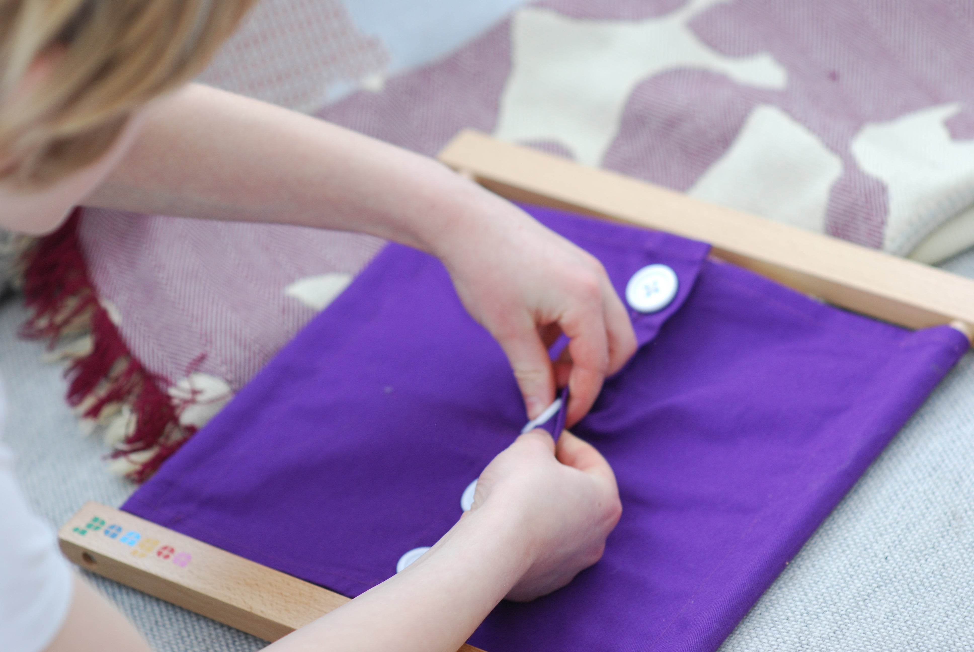 Barn som lærer seg å kneppe knapper med Montessori knapperamme